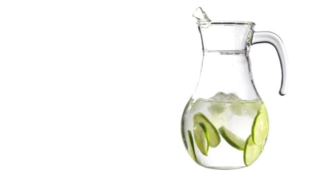 Pieces of ice fall from above into a glass jug with water and lemon limes slices, isolated on a white background. Clean water, detox and loosing weight concept. Copy space for your text. - Footage, Video