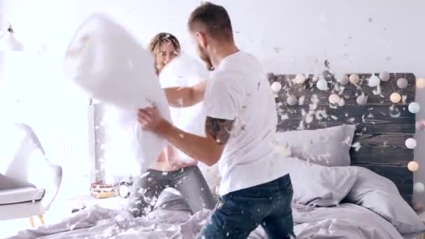Young couple during pillow fight among feathers falling  - Footage, Video