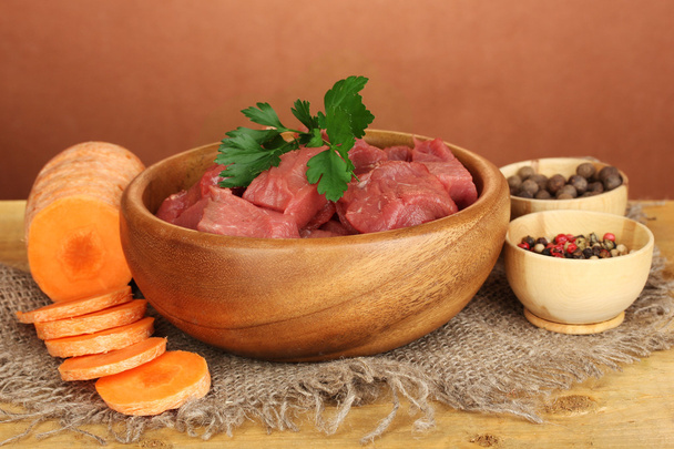 Raw beef meat marinated with herbs and spices on wooden table on brown background - Photo, Image