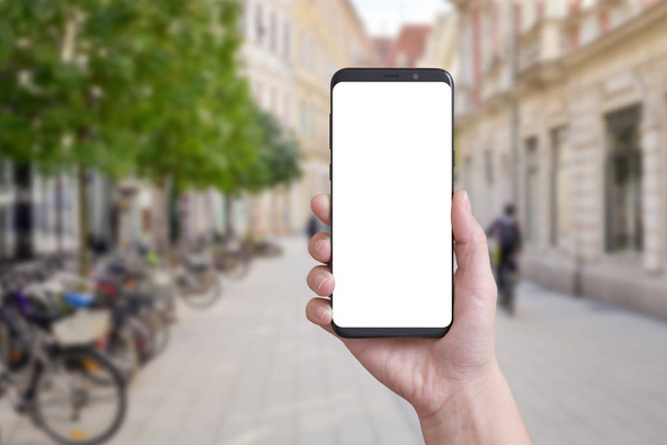 Okos telefon a nő kezében a város utcáin. Elszigetelt képernyő makett, app design bemutatása. - Fotó, kép