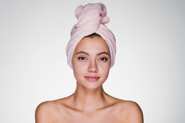 woman with a towel on her head after a shower on a gray background - Φωτογραφία, εικόνα