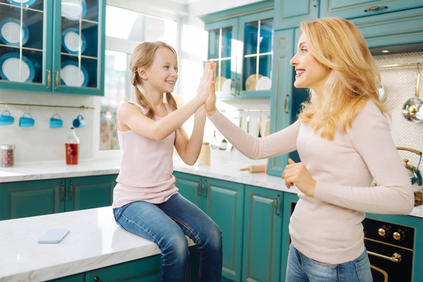Smiling mother and daughter giving a high-five - 写真・画像
