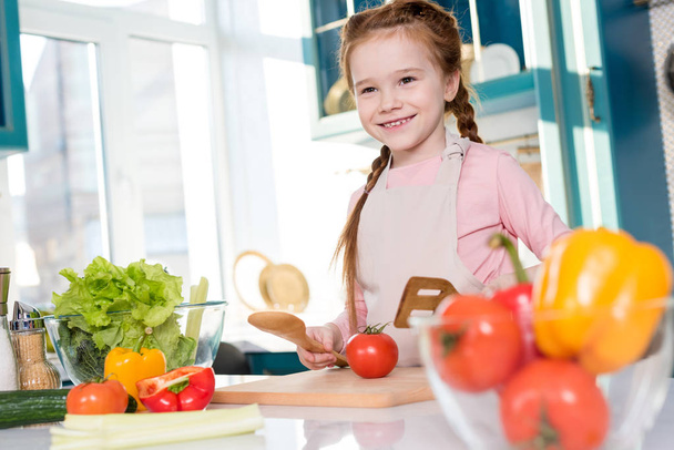 милый счастливый ребенок в фартуке приготовления пищи на кухне
 - Фото, изображение