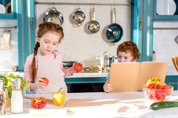 children with cookbook and vegetables cooking together in kitchen - Foto, Imagem