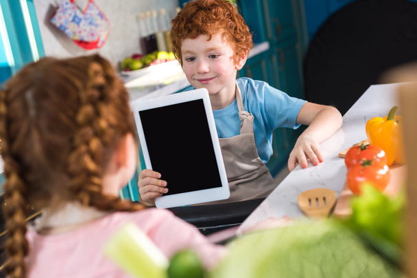 crianças adoráveis usando tablet digital enquanto cozinham juntos na cozinha
 - Foto, Imagem