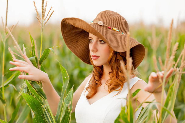 田舎屋外でトウモロコシ畑で帽子の少女. - 写真・画像