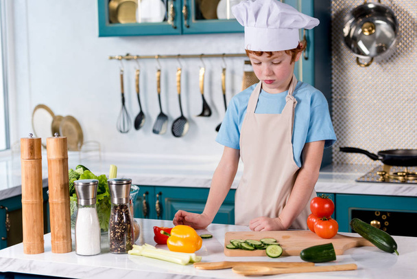 милый маленький мальчик в шляпе шеф-повара и фартук приготовления пищи на кухне
 - Фото, изображение