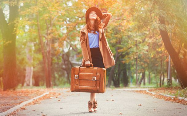 junge rothaarige Frau mit Koffer im Herbst Saison Park.  - Foto, Bild
