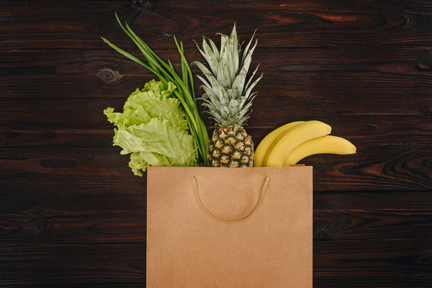 вид на китайскую капусту, ананас и бананы в сумке для покупок на деревянном столе
 - Фото, изображение