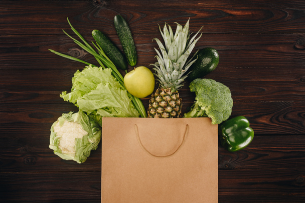 Widok z góry zielone warzywa i owoce w torba na zakupy na drewnianym stole - Zdjęcie, obraz