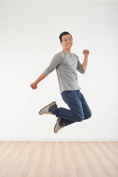 Full-length portrait of young happy Asian man jumping - Fotó, kép