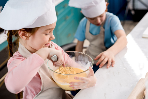 cute little child in chef hat making dough while brother sitting behind - Фото, зображення