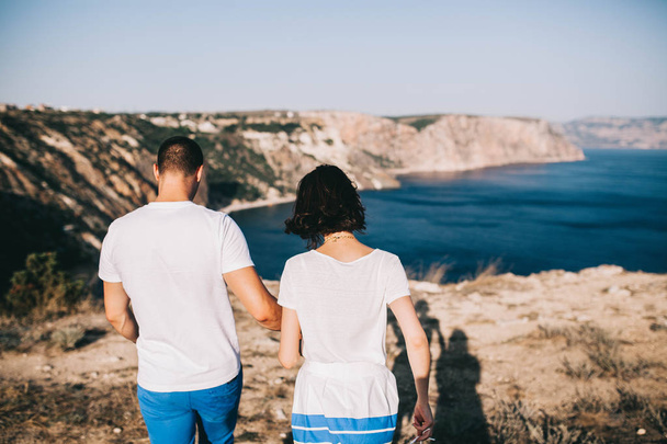jeune couple amoureux marchant sur un rocher avec une belle vue sur la mer et les montagnes
 - Photo, image