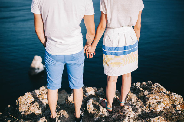 young loving couple walking on a rock with a beautiful view of the sea and mountains - Фото, изображение