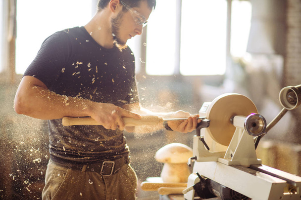 man working at small wood lathe, an artisan carves piece of wood - Foto, Bild