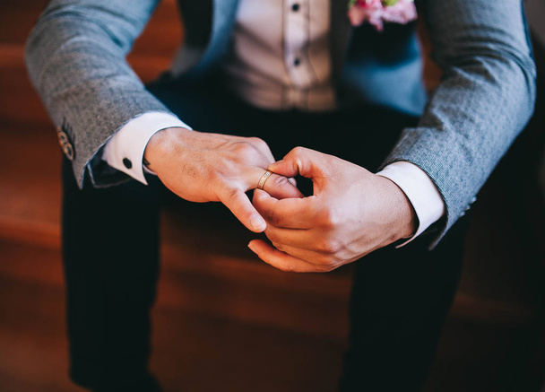 Γάμος το πρωί, ο γαμπρός κατέχει ένα δαχτυλίδι αρραβώνων για τα χέρια του - Φωτογραφία, εικόνα