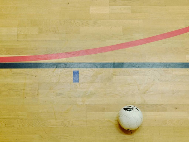 Futsalball und rote und schwarze Linien auf dem Sportboden aus Hartholz. Erneuerung Holzboden  - Foto, Bild