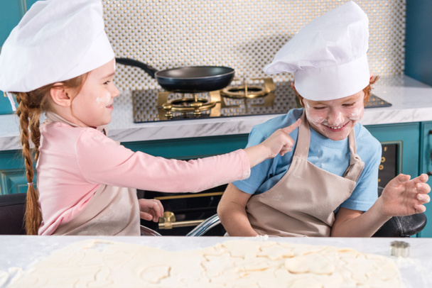 cute little children in chef hats having fun with flour in kitchen - Fotoğraf, Görsel