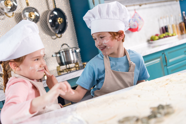 cute little kids in chef hats having fun with flour in kitchen - Fotoğraf, Görsel