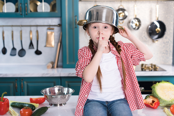 cute child with pan on head looking at camera and gesturing for silence - Фото, зображення