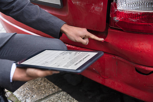 Insurance Agent's Hand Filling Insurance Claim Form On Digital Tablet After Car Accident - 写真・画像