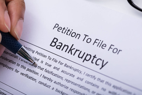 Close-up Of A Person's Hand Filling Bankruptcy Form - Foto, afbeelding
