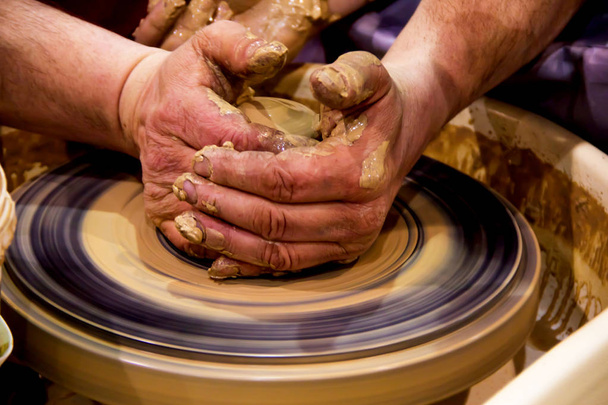 Pottery making a jar of raw clay on a potter's machine with men's hands - Photo, Image