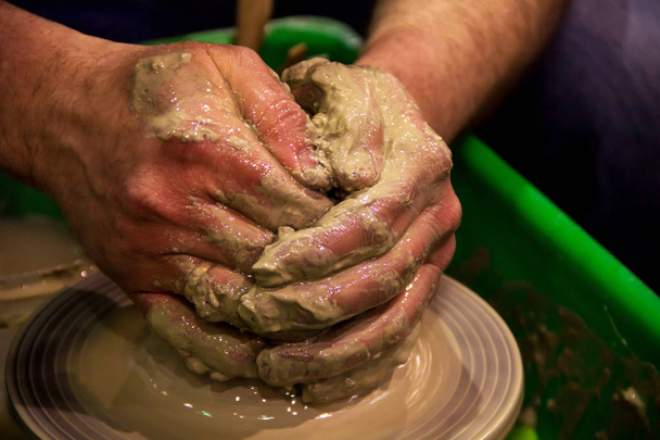 Making a jar of raw clay on a potter's machine with men's hands. Pottery old fashion craft - Photo, Image