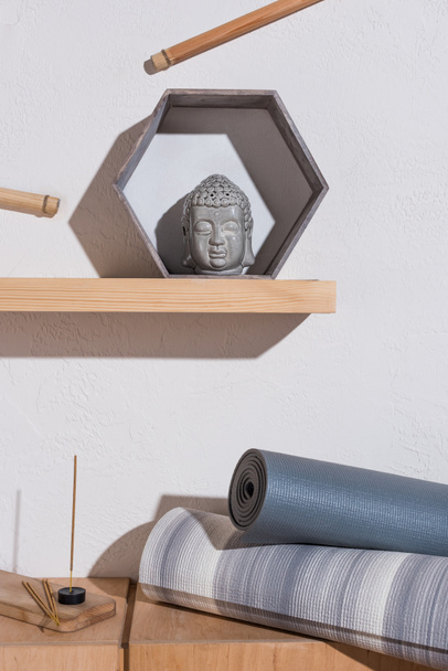 sculpture de tête de bouddha dans un cadre et tapis de yoga avec bâtons d'encens
 - Photo, image
