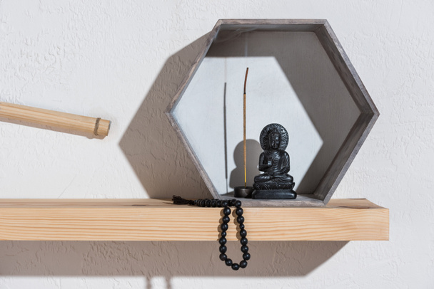 small statue of buddha in frame on wooden shelf - Fotografie, Obrázek