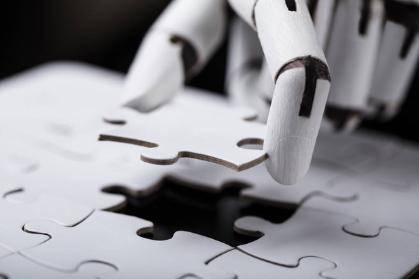 Close-up Of A Robot's Hand Holding Jigsaw Puzzle - Foto, imagen
