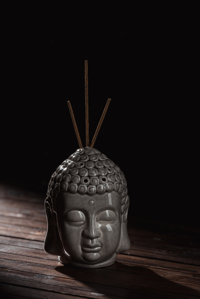 escultura de la cabeza de buda con varillas de incienso
 - Foto, imagen