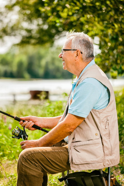 Щасливий старший чоловік рибалить у сонячний день
.  - Фото, зображення