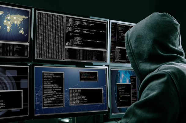 Rear View Of A Hacker Using Multiple Computers For Stealing Data In Office - Фото, изображение
