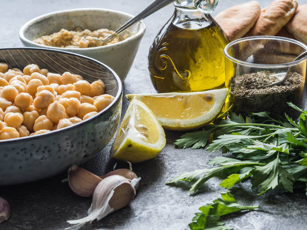 Homemade hummus ingredients. Nut, tahini, lemon, olive oil, garlic, cumin, parsley and mini-pita - Фото, зображення