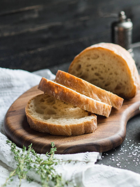 Brot in Scheiben geschnitten auf Holzbrett mit Thymian, Salz und Gewürzen - Foto, Bild