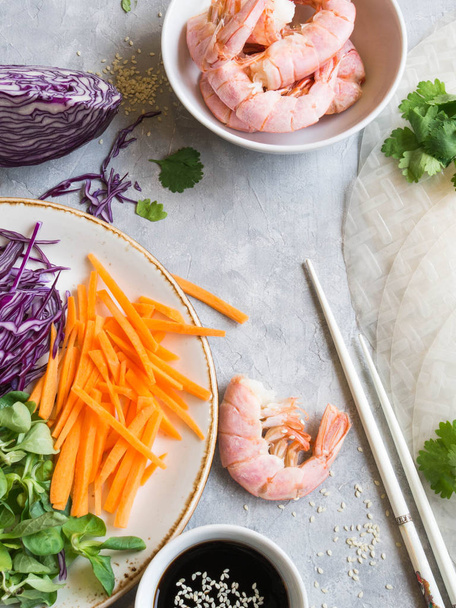 Ingrédients pour la cuisson des rouleaux de printemps - carottes, salade de maïs, chou rouge, crevettes, papier de riz sur fond gris
 - Photo, image