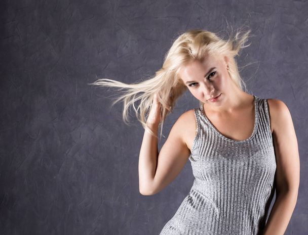 blonde woman with hair in the wind. sexy girl with flying hair on a gray background - Photo, image