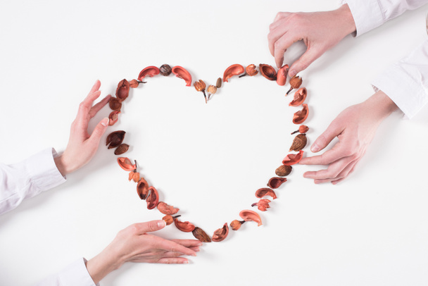 cropped image of couple making heart from dried fruits on valentines day isolated on white - Valokuva, kuva