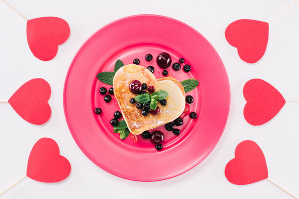 Draufsicht auf herzförmigen Pfannkuchen mit Beeren isoliert auf weißem, Valentinstag-Konzept - Foto, Bild