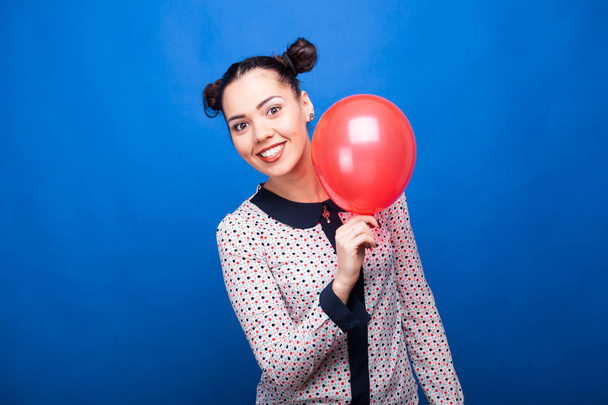 Hymyilevä nainen, jolla on punainen ilmapallo kädessään
 - Valokuva, kuva