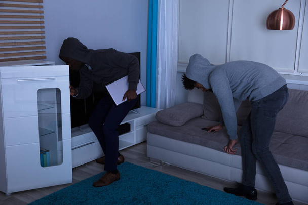 Two Burglar In Hooded Top Stealing Laptop And Cellphone In The House At Night - Foto, immagini