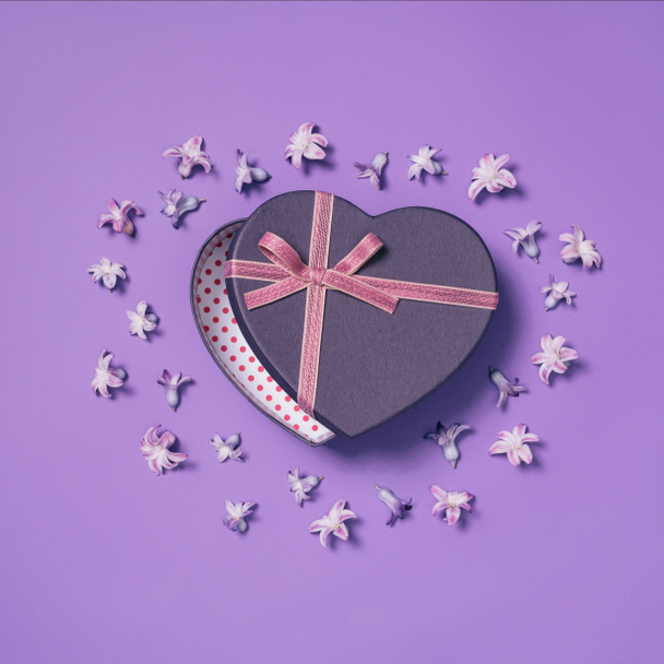 top view of heart shaped gift box with flowers around isolated on purple - Φωτογραφία, εικόνα