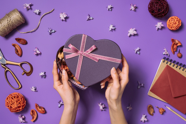 cropped shot of woman opening heart shaped gift isolated on purple - Photo, Image
