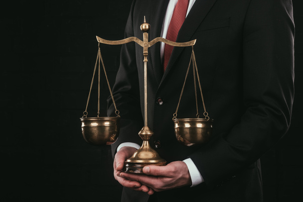 обрезанный снимок адвоката, держащего чешуи изолированные на черном
 - Фото, изображение