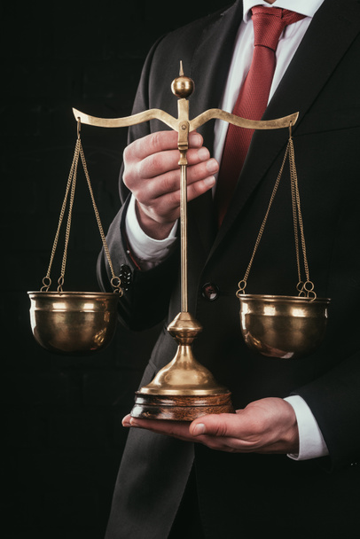 обрезанный снимок адвоката, держащего весы правосудия изолированные на черном
 - Фото, изображение