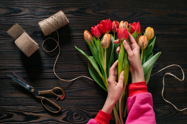 részleges kilátás női kéz, kötél, olló és csokor virágot fa felülettel - Fotó, kép