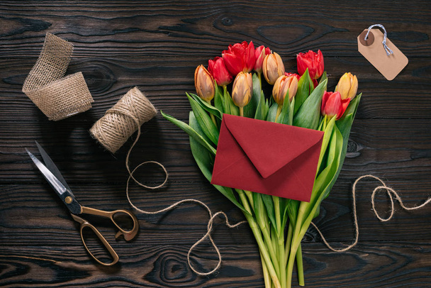 flat lay with bouquet of tulips, envelope and decoration supplies on wooden tabletop - Fotoğraf, Görsel