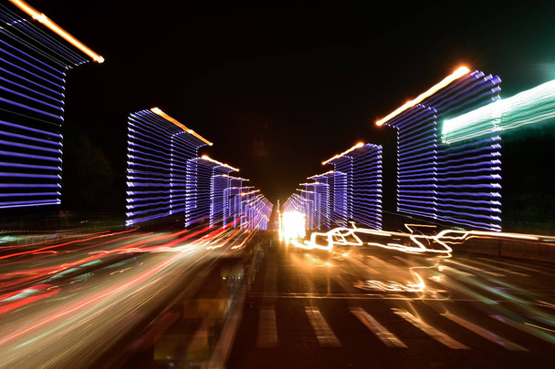 Tiellä on abstrakteja autojälkiä. Abstrakti kuva yöliikennevalosta kadulla
. - Valokuva, kuva