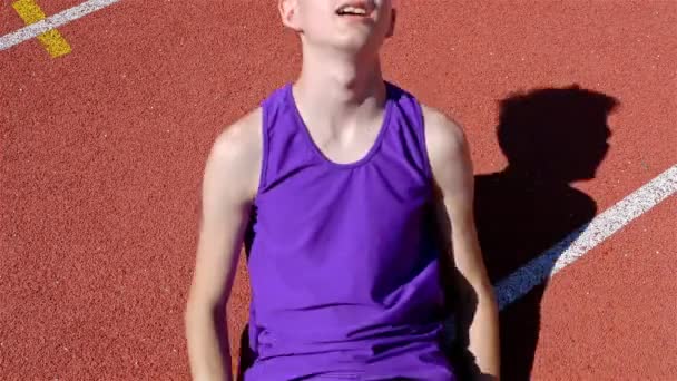 Stopa běžec chlapec dospívající ležící na vybité unavený na stadionu trať, 4k - Záběry, video